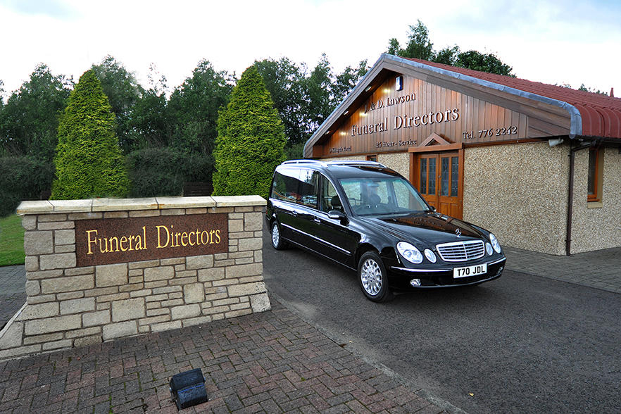 The outside of J&D Lawson Funeral Directors building with a hearse parked on the driveway
